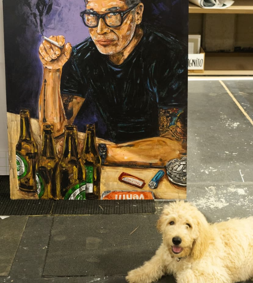 A large painted portrait waiting in the workshop, the studio dog lying in front of it