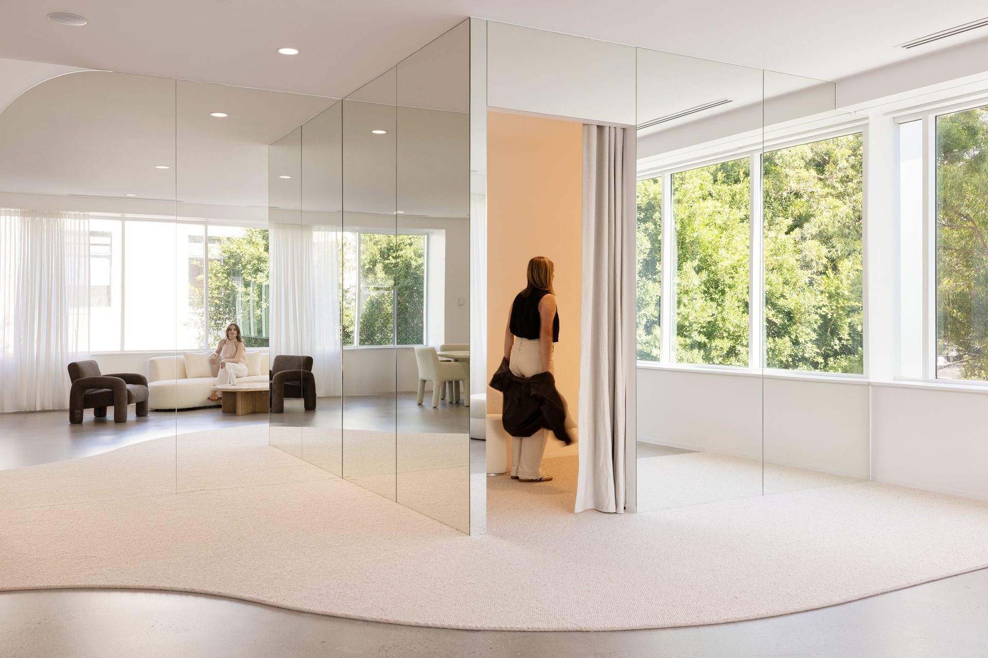 Frameless full-height mirror panels wrapping a curtained fitting room in a bright open lounge