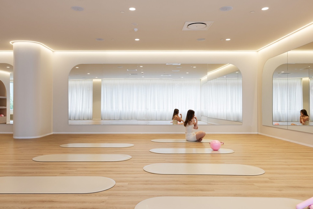 A Pilates studio with a timber floor, mats and wide mirrors with rounded top corners along the walls