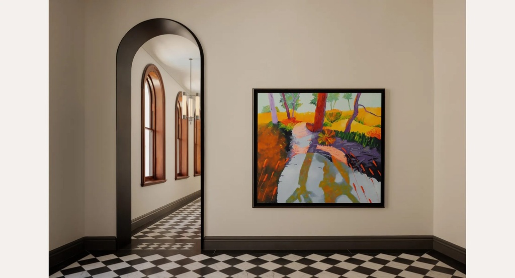 A square landscape painting of a red tree trunk beside a path, in a dark frame, next to an arched doorway over a chequered floor